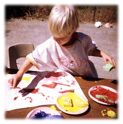 A photograph of a child painting outdoors